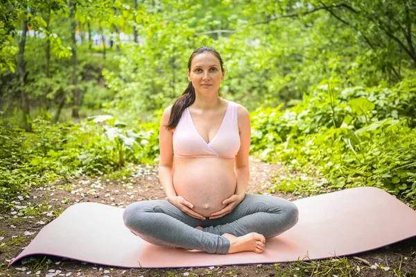아름다운 임산부가 야외에서 요가를 있어요 분홍색 앉아서 미래의 어머니는 스포츠 — 스톡 사진