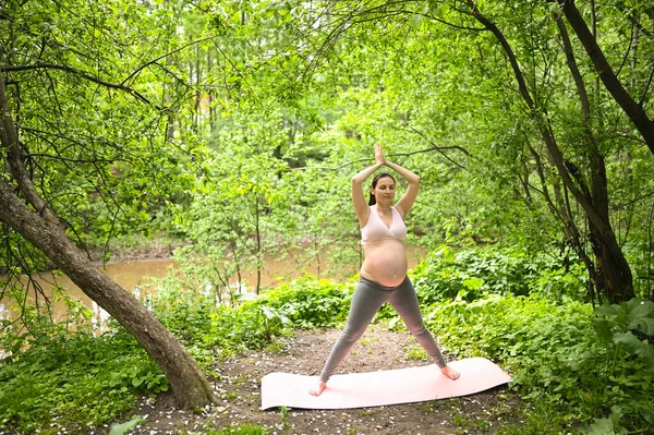 美丽的年轻孕妇在户外公园做瑜伽运动 坐在粉色瑜伽垫上休息 积极的未来母亲运动的生活方式 健康怀孕概念 — 图库照片