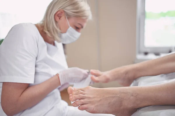 在美容院 教育家用专用工具进行专业的医学修脚手术 在Spa沙龙进行足部治疗 Podiatry诊所美容师 手戴白色手套 腿为女性 — 图库照片