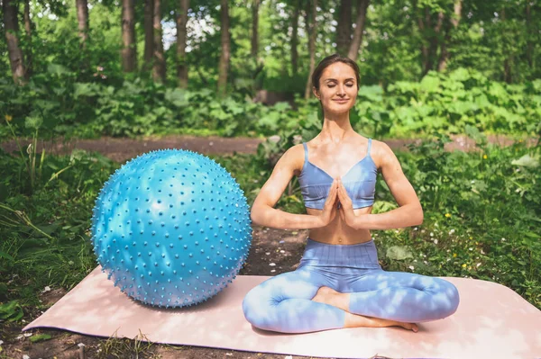肌肉纤细迷人的女性 扁平的腹部完美的身体 美丽的年轻适合做瑜伽练习的女子与健身普拉提蓝色球在夏季公园室外 运动的生活理念 — 图库照片