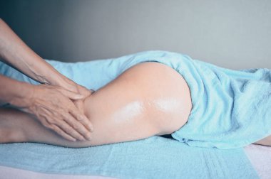 Masaj masasında uzanmış terapi masajından zevk alan tanınmayan genç bir kadın. Vücut bakımı, kilo verme konsepti. El masajı terapisti spa kliniğinde anti-selülit masaj yapıyor.