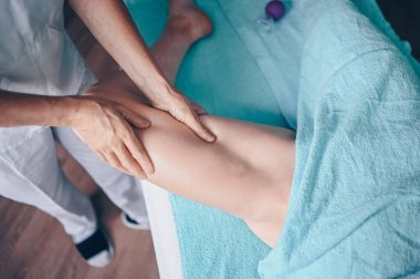 Masaj masasında uzanmış terapi masajından zevk alan tanınmayan genç bir kadın. Vücut bakımı, kilo verme konsepti. El masajı terapisti spa kliniğinde anti-selülit masaj yapıyor.