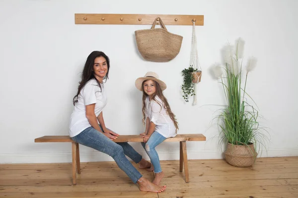母亲给女儿戴上一顶草帽 坐在斯堪的纳维亚风格的长椅上 快乐的爱着家人 在家里散步很开心 — 图库照片