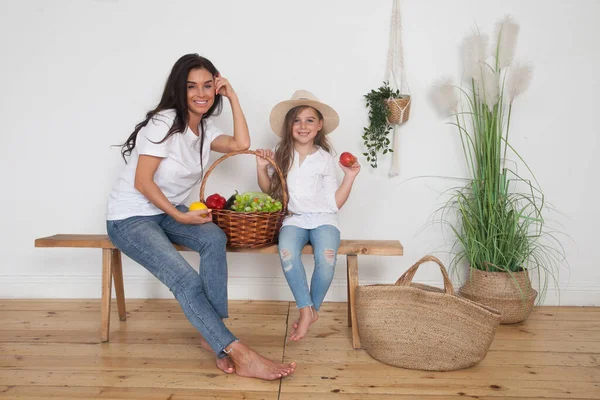 母亲和她的小女儿戴着草帽坐在斯堪的纳维亚风格的长椅上 摆着有机农场果篮 快乐的爱着家人 在家里散步很开心 — 图库照片