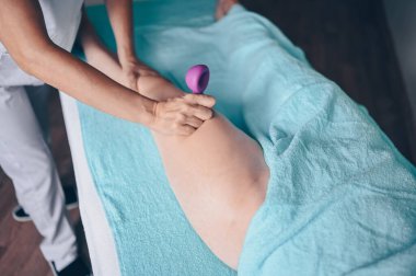 Masaj masasında uzanmış terapi masajından zevk alan tanınmayan genç bir kadın. Vücut bakımı, kilo verme konsepti. El masajı terapisti spa kliniğinde anti-selülit masaj yapıyor.