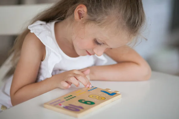 Anaokulunda masa başında otururken tahta matematiksel çok renkli figürlerle eğitici oyunlar oynayan küçük tatlı anaokulu çocuğu. Okul konseptine dönelim.