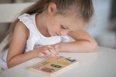 Anaokulunda masa başında otururken tahta matematiksel çok renkli figürlerle eğitici oyunlar oynayan küçük tatlı anaokulu çocuğu. Okul konseptine dönelim.