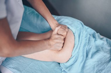 Masaj masasında uzanmış terapi masajından zevk alan tanınmayan genç bir kadın. Vücut bakımı, kilo verme konsepti. El masajı terapisti spa kliniğinde anti-selülit masaj yapıyor.