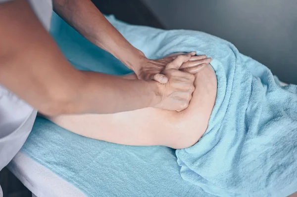 Masaj masasında uzanmış terapi masajından zevk alan tanınmayan genç bir kadın. Vücut bakımı, kilo verme konsepti. El masajı terapisti spa kliniğinde anti-selülit masaj yapıyor.