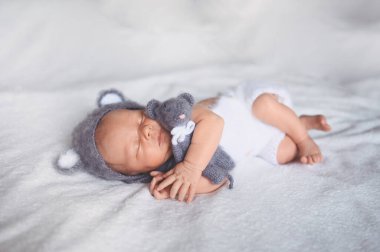 Örgü bir takım elbiseyle beşikte uyuyan yeni doğmuş tatlı bir bebek. Bebek eşyaları paketleme şablonu. Sağlıklı çocuk, hastane kavramı ve mutlu annelik. Bebek, bebek. Çocuk odası..