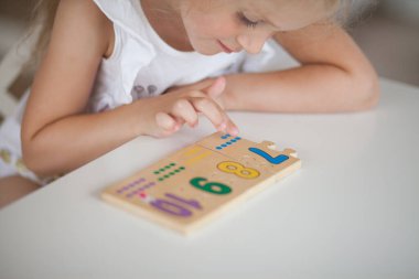 Anaokulunda masa başında otururken tahta matematiksel çok renkli figürlerle eğitici oyunlar oynayan küçük tatlı anaokulu çocuğu. Okul konseptine dönelim.