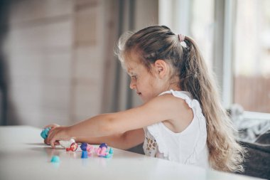 Anaokulunda okula hazırlanırken masada oturan, plastik figürlerle eğitim oyunları oynayan küçük tatlı anaokulu çocuğu. Okul konseptine dönelim.