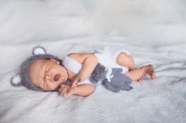Şirin, yeni doğmuş bebek bebek beşikte kulakları olan örgü bir takım elbiseyle uyuyor. Bebek eşyaları paketleme şablonu. Sağlıklı çocuk, hastane kavramı ve mutlu annelik. Bebek, bebek. Çocuk odası.