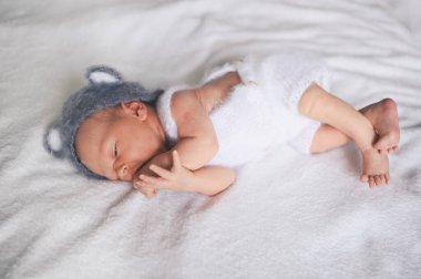 Sevimli, yeni doğmuş bebek bebek beşikte kulakları olan örgü bir takım elbiseyle uyuyor. Bebek eşyaları paketleme şablonu. Sağlıklı çocuk, hastane kavramı ve mutlu annelik. Bebek, bebek. Çocuk odası.