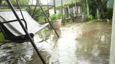 Şiddetli yağmurda kırsal kesimdeki yazlıkta rüzgarda sallanarak. Yağmur damlaları ve asfalttaki büyük su birikintileri..