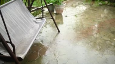 Şiddetli yağmurda kırsal kesimdeki yazlıkta rüzgarda sallanarak. Yağmur damlaları ve asfalttaki büyük su birikintileri..