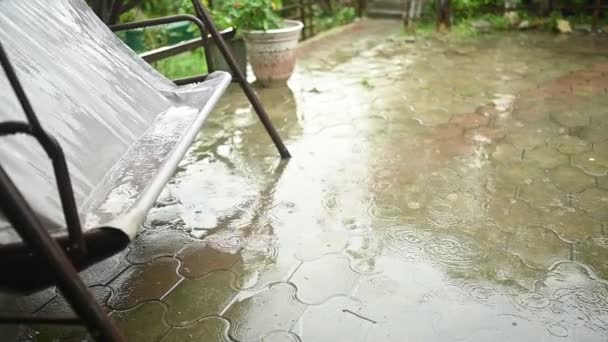 Balançoire dans le vent balançoire de campagne humide dans la maison de campagne sous de fortes pluies. Cercles de gouttes de pluie et d'énormes flaques sur l'asphalte. — Video