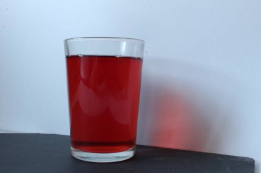 Çilek kirazından bir bardak kırmızı meyve suyu ya da beyaz arka planda şarap.