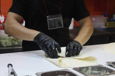Bir adam eldivenli bir Shawarma hazırlar.