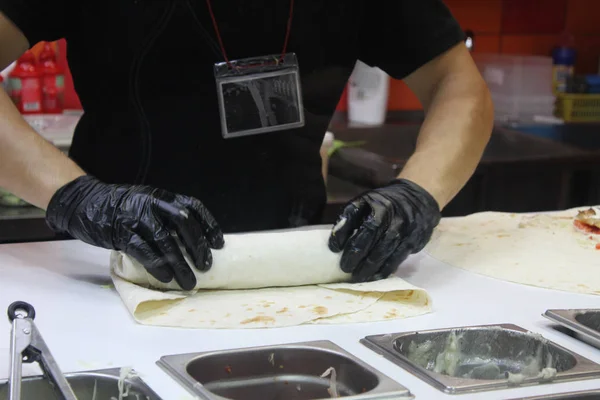 Bir adam eldivenli bir Shawarma hazırlar.