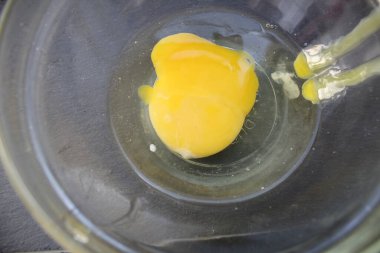 Yumurta cam bir kaseye kırılır. Kırık yumurta sarısı olan bir tabak. Kahvaltıda çırpılmış yumurta.