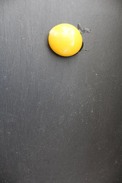 鶏の卵の黄身か桃の半分は灰色の石の黒の背景の角にあり — ストック写真