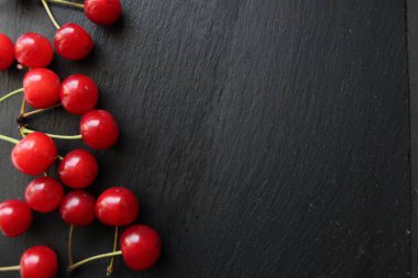 Çilek yemek için arka plan sağ arka planda sol ya da alt tarafa saçılmış kirazlar gri bir taş üzerinde metin eklemek için bir yer var