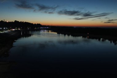 Nehrin üzerinde gün batımı mavi ve kırmızı gökyüzü yıldızlar ve ağaçların ormanı suyu yansıtıyordu.