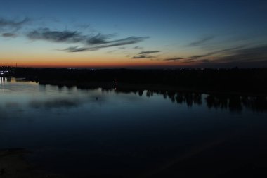 Nehrin üzerinde gün batımı mavi ve kırmızı gökyüzü yıldızlar ve ağaçların ormanı suyu yansıtıyordu.