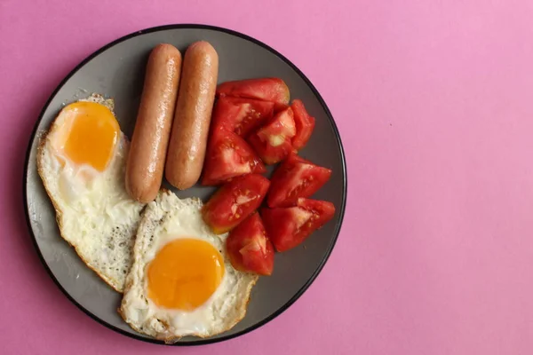 伝統的な英語ヨーロッパの朝食ソーセージ卵サラダ野菜赤トマトピンクの背景のプレート上のコピースペースのビューまたはトップビュー — ストック写真