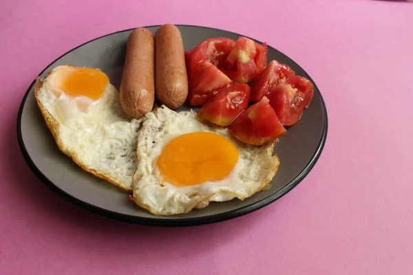 伝統的な英語ヨーロッパの朝食ソーセージ卵サラダ野菜赤トマトピンクの背景のプレート上のコピースペースのビューまたはトップビュー — ストック写真
