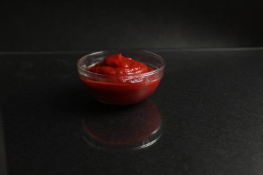 Cam kasede kırmızı domates sosu, siyah arka planda et sosu. Kopya alanı.