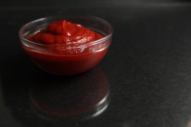 Cam kasede kırmızı domates sosu, siyah arka planda et sosu. Kopya alanı.