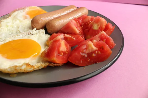 传统的英式欧洲早餐腊肠鸡蛋沙拉蔬菜红色西红柿盘粉红背景复制空间侧面视图或顶部视图 — 图库照片