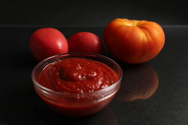 Een Glazen Steelpan Met Rode Tomatensaus Staat Een Zwarte Achtergrond — Stockfoto