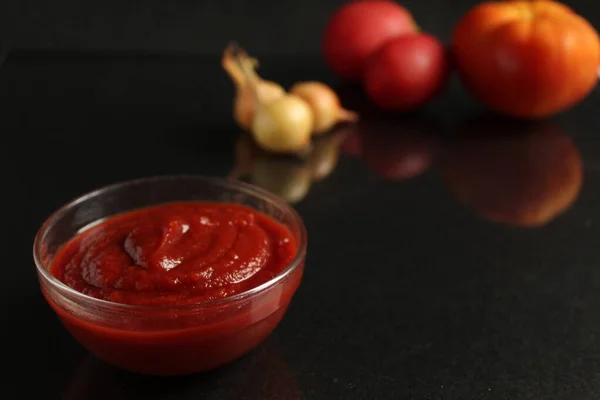 Een Glazen Steelpan Met Rode Tomatensaus Staat Een Zwarte Achtergrond — Stockfoto