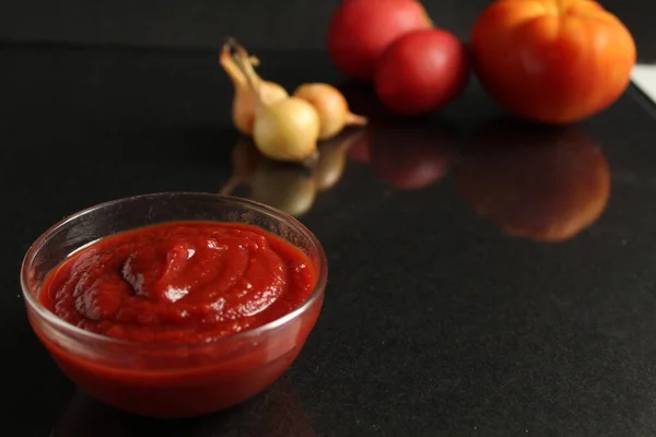 Een Glazen Steelpan Met Rode Tomatensaus Staat Een Zwarte Achtergrond — Stockfoto