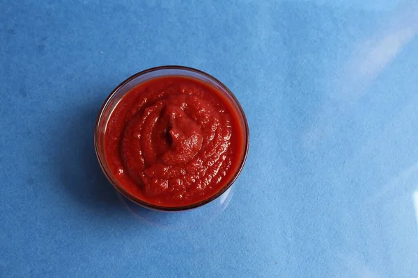 キッチンカフェレストランのためのスペースと青の背景にガラス鍋に赤トマトソース — ストック写真