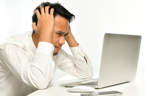 Stressed and upset business man pulling his hair while working on a computer in the office