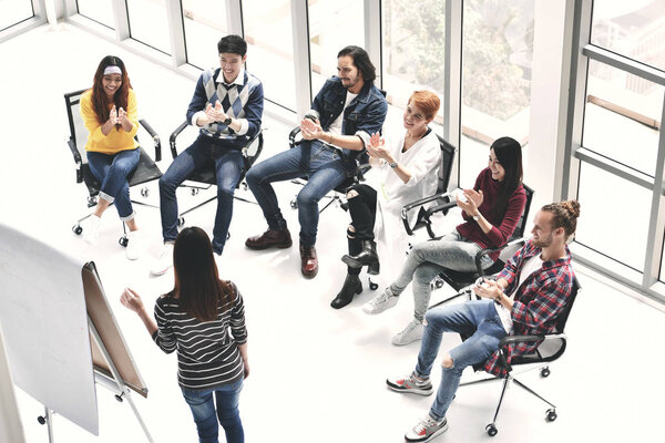 Group of businesspersons cheering and clupping for a co-worker at the office