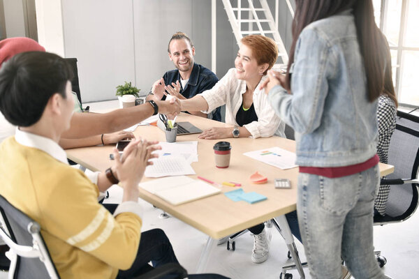 Two businesspersons shaking hands in agreement in casual business setting at office