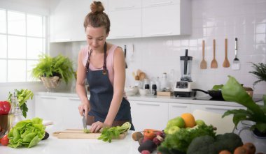 Genç kadında sağlıklı sebze kesme ve sağlıklı yemek ve salata hazırlama bir mutfak