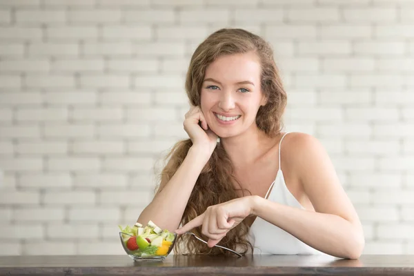 Beautiful young woman in joyful postures with salad bowl on the side
