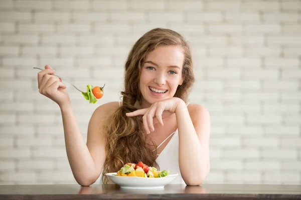 Beautiful young woman in joyful postures with salad bowl on the side