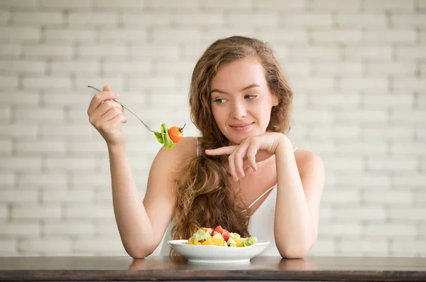 Beautiful young woman in joyful postures with salad bowl on the side