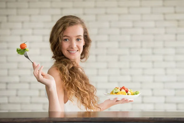 Beautiful young woman in joyful postures with hand holding salad bowl