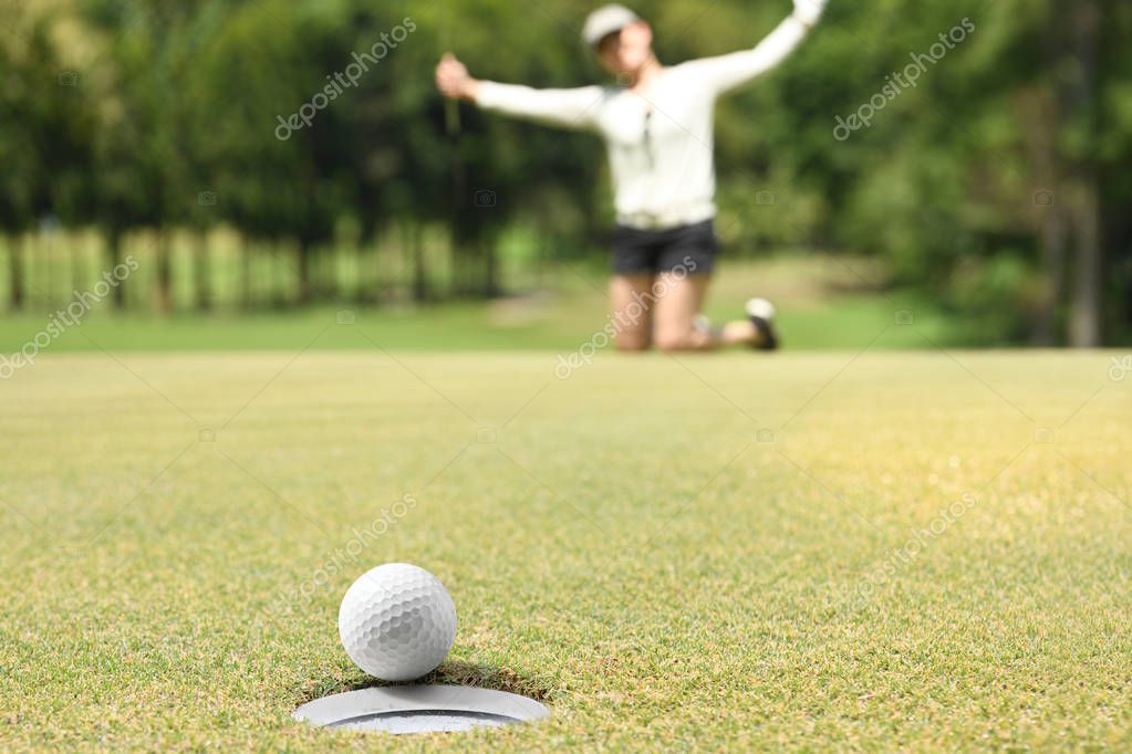 Woman golfer cheering after a golf ball on a golf green