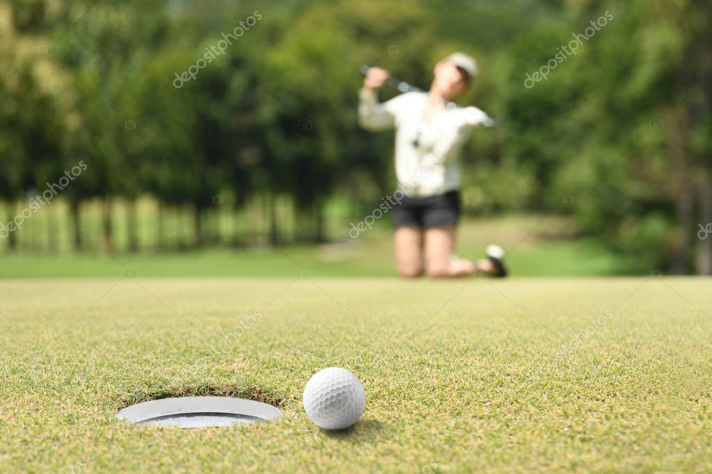 Woman golfer feeling disappointed after a putted golf ball missed the hole