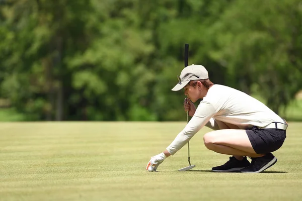 女子高尔夫球运动员检查线在绿色草地上放置高尔夫球 — 图库照片