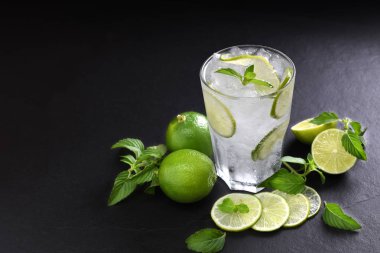 Siyah arka plan üzerine dilimlenmiş limon ile cam içki taze limon soda